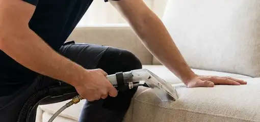 Professional upholstery cleaner deep-cleaning a fabric sofa with a handheld extraction tool, Evansville, IN.